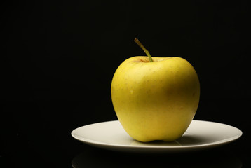 Apple on saucer on black background