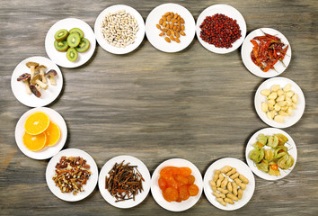 Different products on saucers on wooden table, top view