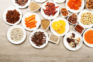 Different products on saucers on wooden table, top view