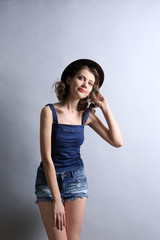 Naklejka premium Portrait of beautiful model in jeans clothing and hat on gray background