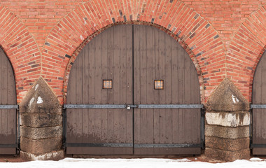 Old locked wooden gate in red brick fortress wal