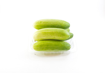 Five green cucumbers stack in plastic tray on white background