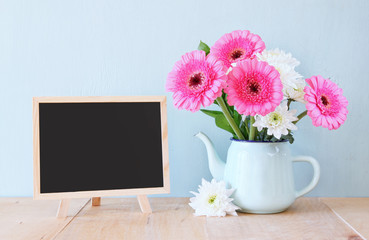 summer bouquet of flowers on the wooden table and blackboard wit