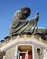 Obraz premium Tian Tan Buddha and red doors leading into a temple under the br