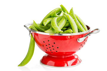 Green peas in red colander and single one on the side, isolated