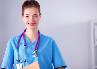 Smiling female doctor with a folder in uniform standing at