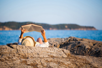 Woman reading a book on the seashore