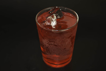 Water in a glass of red on a black background.