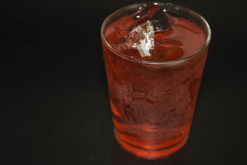 Water in a glass of red on a black background.
