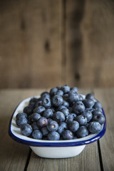 Blueberries in rustic kitchen setting with old wooden background