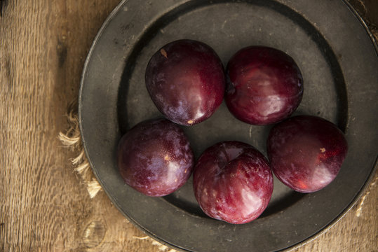 Fresh plums in natural light setting with moody vintage retro st