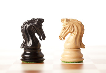 Confrontation - white and black chess knights on white © lusia83