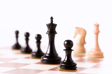 Black chess pieces on a chessboard standing in perspective