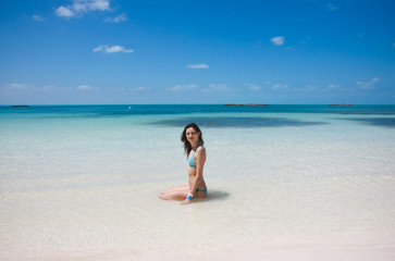 Young beautiful woman sitting in the tropical blue sea on the wh