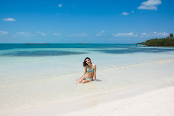 Young beautiful woman sitting in the tropical blue sea on the wh