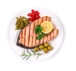 Grilled salmon steak with vegetables on plate.