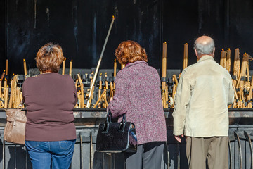 Pilgrims burning votive candles as fulfillment of vows - obrazy, fototapety, plakaty