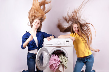 Girl sitting on the washing machine with the laundry for washing