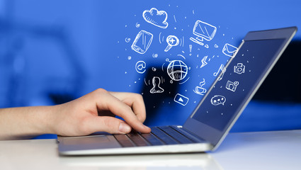 Hand writing on notebook computer with media icons