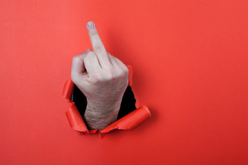 Make a fuck sign by use his hands through hole on the red paper.