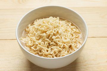 Instant noodles in white dish on wood background