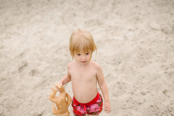 Toddler girl at the beach playing with her baby doll