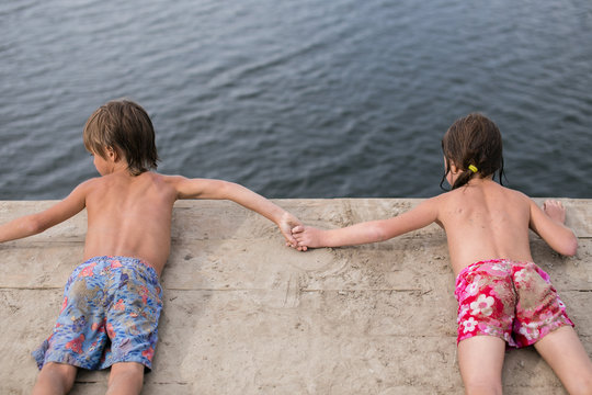 Fraternal twins tanning on wooden deck at the lake