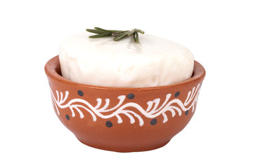 Goat cheese with a sprig of rosemary in a clay bowl with a patte