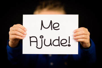 Child holding sign with Portuguese words Me Ajude - Help Me