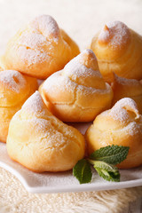 Fresh eclairs with powdered sugar and mint close up. vertical