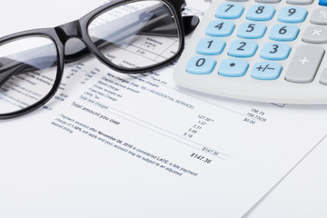 Neat calculator with pen, glasses and utility bill under it