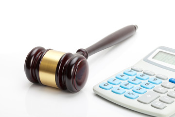 Wooden judge's gavel and calculator next to it