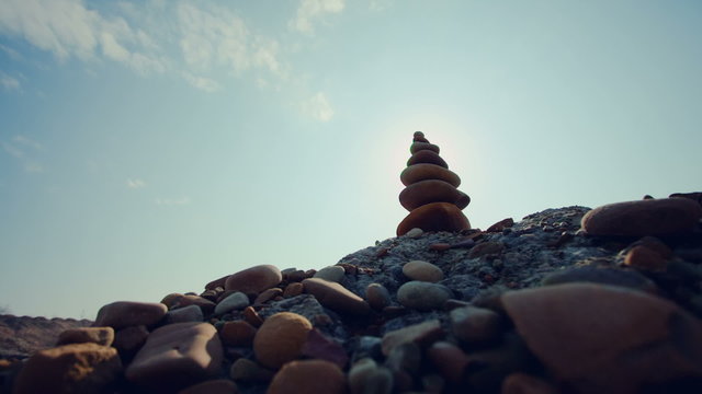 Stone tower on a pebble beach again blue sky