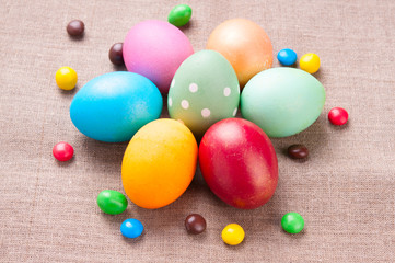 Group of colorful Easter eggs and colored candies lying on linen