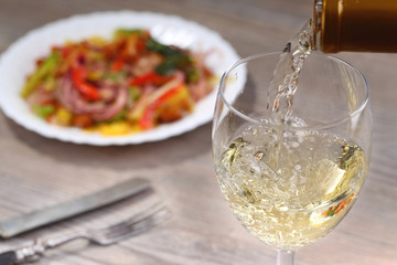 Pouring white wine and salad