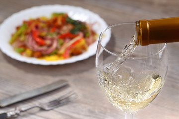 Pouring white wine and salad