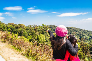 Mother and daughter see mountain and blue sky.