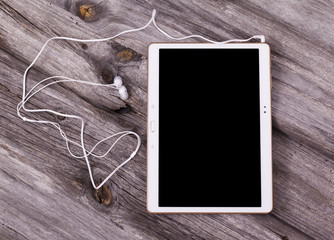 Digital tablet computer with earphones against wooden background