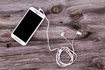 Smart phone with earphones against wooden background