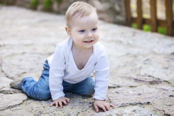 Cheerful little boy crawling on stone paved sidewalk