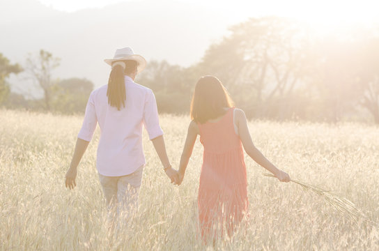 Asian young couple holding hand, walking under nature sunlight
