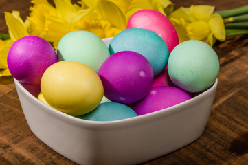 Bowl of dyed Easter eggs with daffodils