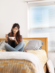 asian teen girl in bedroom eating soup