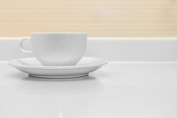 A white ceramic cup with saucer on counter top