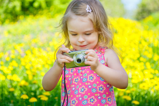 Little girl taking pictures on a meadow
