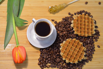 closeup of a cup of black coffee, two waffles on coffee beans, f