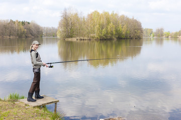 Fototapeta na wymiar woman fishing on pier at pond