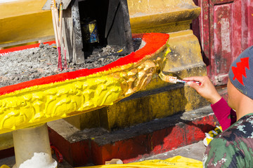 The worker is painting gold color on joss stick pot