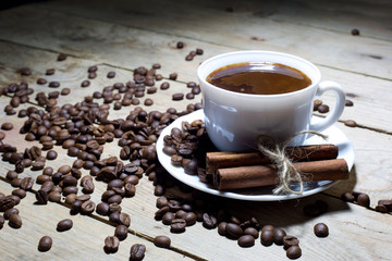 Cup of Coffee with Cinnamon and Coffee Beans on Wooden Table