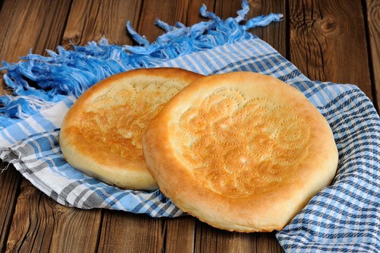 Fatir, uzbek flatbread on blue arab scarf on wooden background